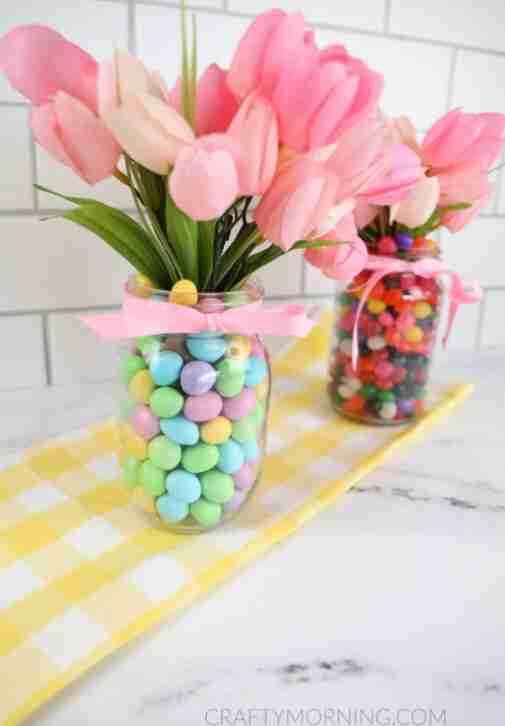 Mason jar and vase with candy and flowers.