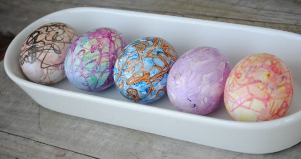 Eggs decorated with crayons on white tray. 
