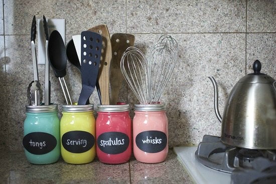 Mason jars painted and holding utensils. 
