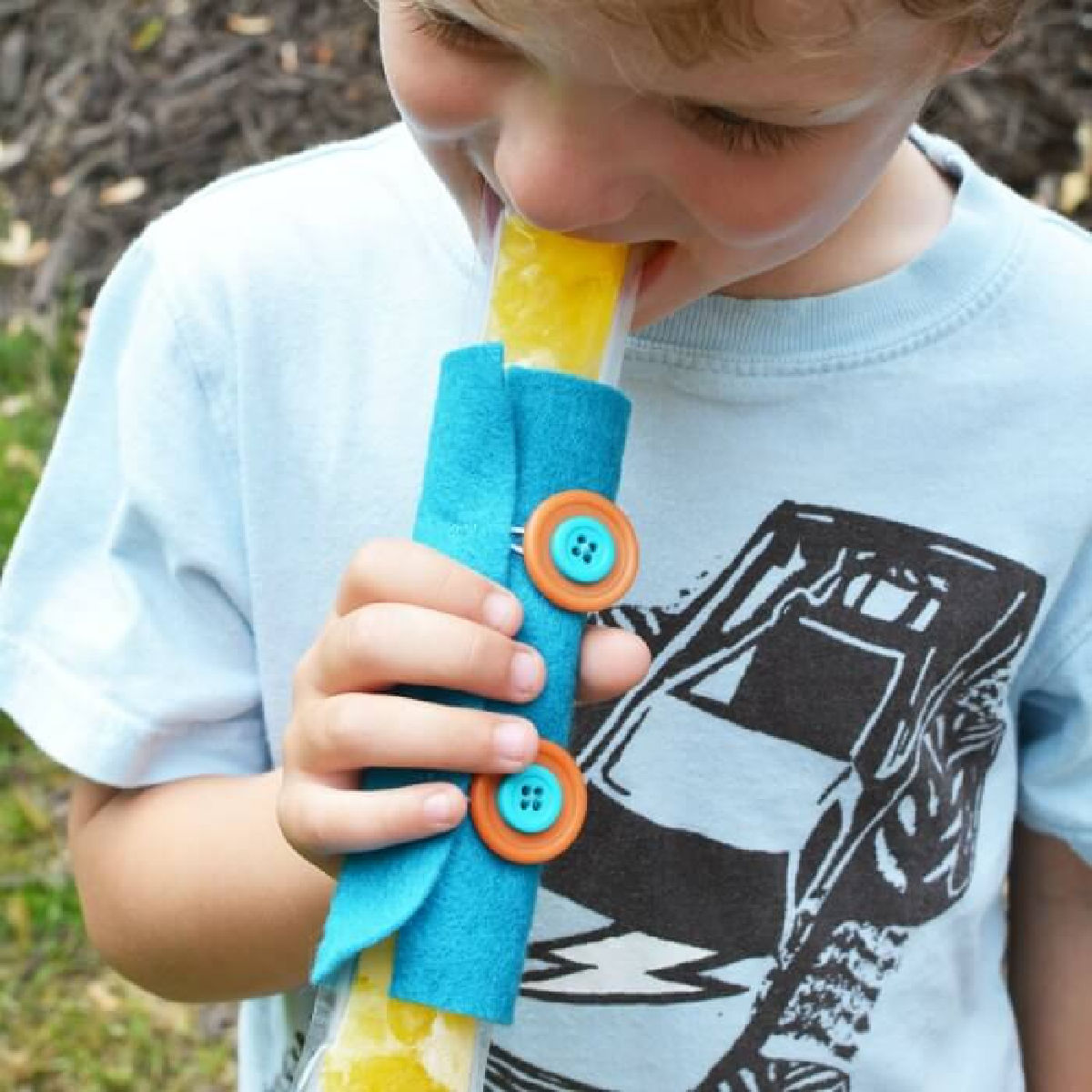 Child holding popsicle in holder. 