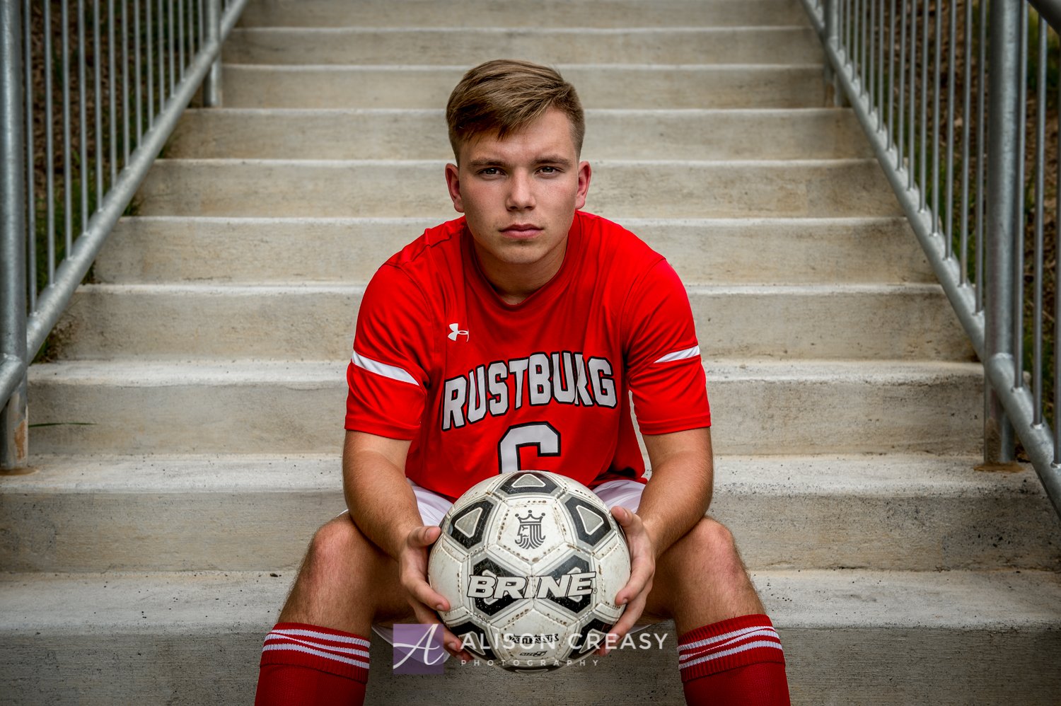 Soccer player on steps sitting down.